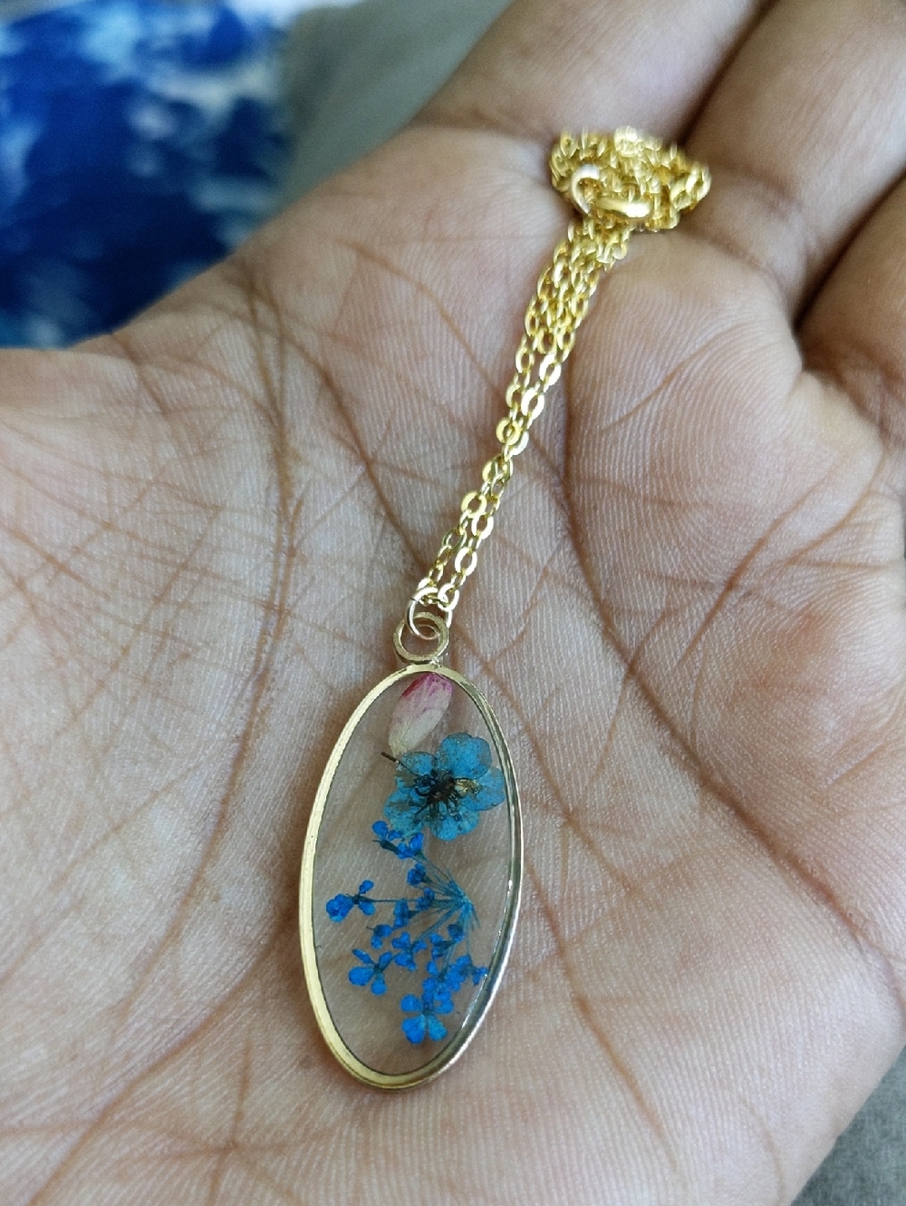 Gold Oval Pendant Necklace with Blue Pressed Flowers Print.
